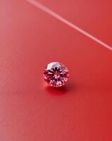 A pink diamond is sitting on a red surface photo