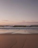 Sunset on the beach with waves crashing in photo
