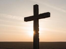 Sunlight shine through silhouette of big wooden Christian cross on open field during sunset. photo