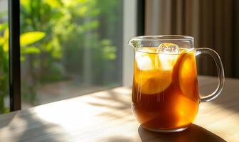 A pitcher of iced tea with lemon slices in a sunlit setting. photo