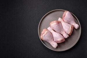 Raw chicken legs with salt, spices and herbs photo