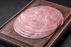 Smoked ham with salt, spices and herbs cut into round slices photo