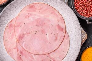 Smoked ham with salt, spices and herbs cut into round slices photo