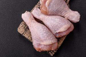 Raw chicken legs with salt, spices and herbs photo