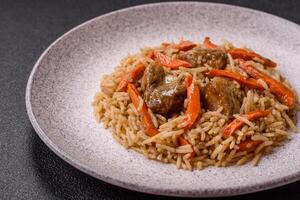 Delicious fresh pilaf with rice, carrots, meat, onions, spices and berries photo