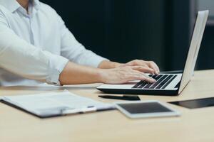 Close-up photo of a business man's hands working and typing on a laptop keyboard, a manager working in the office at a table.