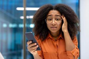 A concerned office worker in an orange shirt looking at camera. The image captures a moment of worry or confusion, highlighting technology and modern communication challenges photo