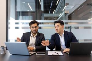 Business professionals having a collaborative discussion in modern office, utilizing laptop and smartphone technology. Teamwork and strategy emphasized in meeting. photo