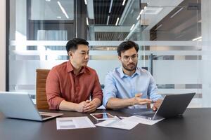 Business professionals in meeting discussing project. Colleagues collaborating over laptop, emphasizing teamwork, technology, strategy. Modern office environment enhances professional interaction. photo