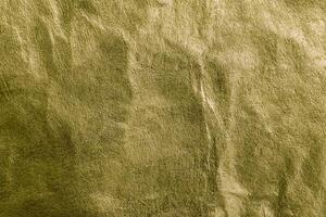 Close-up of gold wrinkled texture with visible grain, ideal as a background for design or abstract concepts. photo