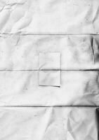 A black and white texture of folded and wrinkled paper with visible creases and subtle stains, perfect for artistic backgrounds or design overlays. photo