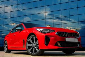 Red car against the background of the evening sky. Stylish, modern, bright image of the car for design solutions. photo