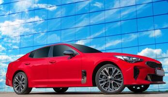 Red car on a blue sky background with white clouds. A stylish, modern, bright image of an avto mobile for design solutions. photo