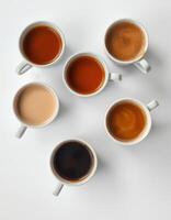 Different varieties of coffee arranged in ceramic mugs on a white surface photo