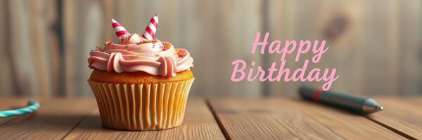 Sweet birthday cupcake with pink frosting, candles, and festive decorations on a wooden table photo