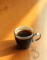 Coffee cup resting on a wooden table with sunlight casting warm shadows photo