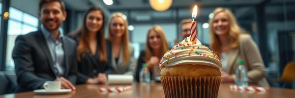 Team celebrates a birthday in the office with a decorated cupcake and joyful camaraderie photo