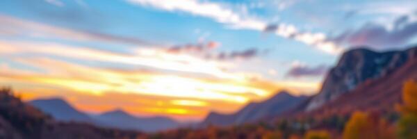 Vibrant sunset casts warm hues over mountain landscape with clouds and silhouettes of peaks in the distance photo