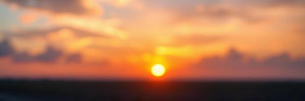Sunset in a blurred landscape showcasing vibrant colors over a tranquil horizon during dusk photo