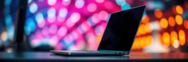 Laptop on a table with colorful lights in the background during a lively evening atmosphere photo