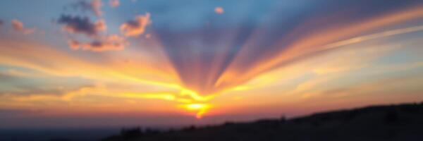 Colorful sunset displaying vibrant rays over the horizon in a serene landscape during evening hours photo