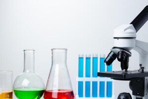 Lab microscope with laboratory glassware on desk photo
