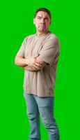 A man stands with arms crossed and a thoughtful expression in front of a green screen photo