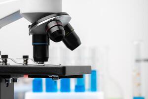 Microscope and test tubes on table in laboratory, close up photo