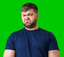Man expressing confusion with crossed arms in front of a bright green background photo