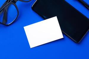 Mock up of blank business card and black smartphone screen on table photo