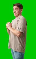 Young man making a disgusted expression while standing against a bright green background photo