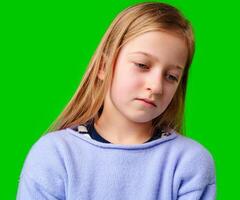 A young child in a light purple sweater gazes against a green background while deep in thought photo