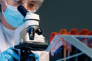 Woman scientist looking through a microscope in laboratory photo