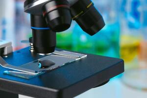 Scientific laboratory with microscope and test tubes with samples, close up photo