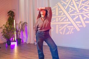 A woman poses in front of a wall with a geometric light projection, in a studio setting photo