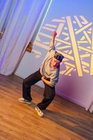 A dancer performs a move in a studio, illuminated by colorful light photo