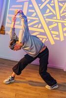A dancer stretches in a studio with a colorful light projection on the wall photo