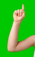 A hand raised with an index finger pointing upwards against a bright green background photo