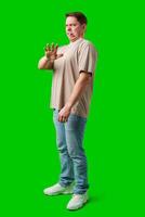 Young man making a disgusted expression while standing against a bright green background photo