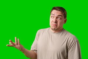 A man stands with arms crossed and a thoughtful expression in front of a green screen photo