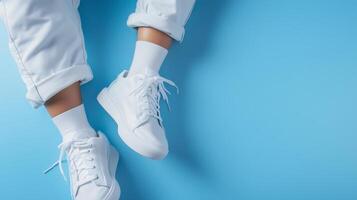 Stylish white sneakers with rolled-up pants against a vibrant blue background photo