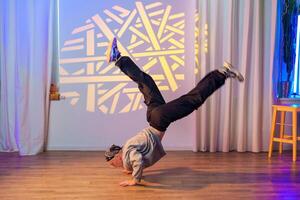 A dancer performs a dynamic move in a studio with a geometric light projection behind him photo