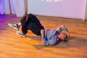 A dancer practices a move on a wooden floor in a studio photo