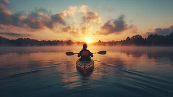 A kayaker glides across a tranquil lake at sunrise, with beautiful colors reflecting on the water photo