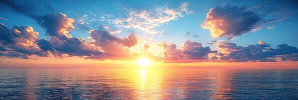 Sunset casts warm colors across a tranquil ocean, with clouds reflecting the golden light in the sky photo