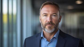Professional man with a beard poses confidently in a bright office with large windows photo