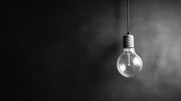 A classic light bulb hangs from a cord against a dark, textured backdrop, creating a nostalgic atmosphere photo