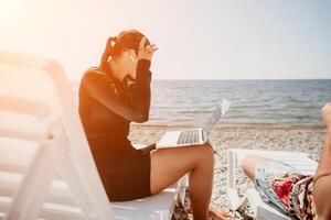 Woman Laptop Beach Work - Businesswoman working on her laptop while on the beach, enjoying a relaxing day while still being productive. photo