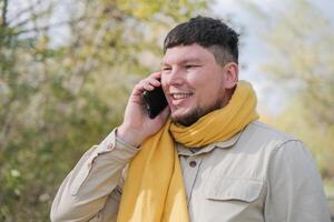 young caucasian man walking in the park and using smartphone photo