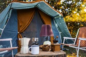 vintage coffee set on the old wooden table In front of the retro cabin tent, retro chairs, Group of camping tents, and soft focus. photo